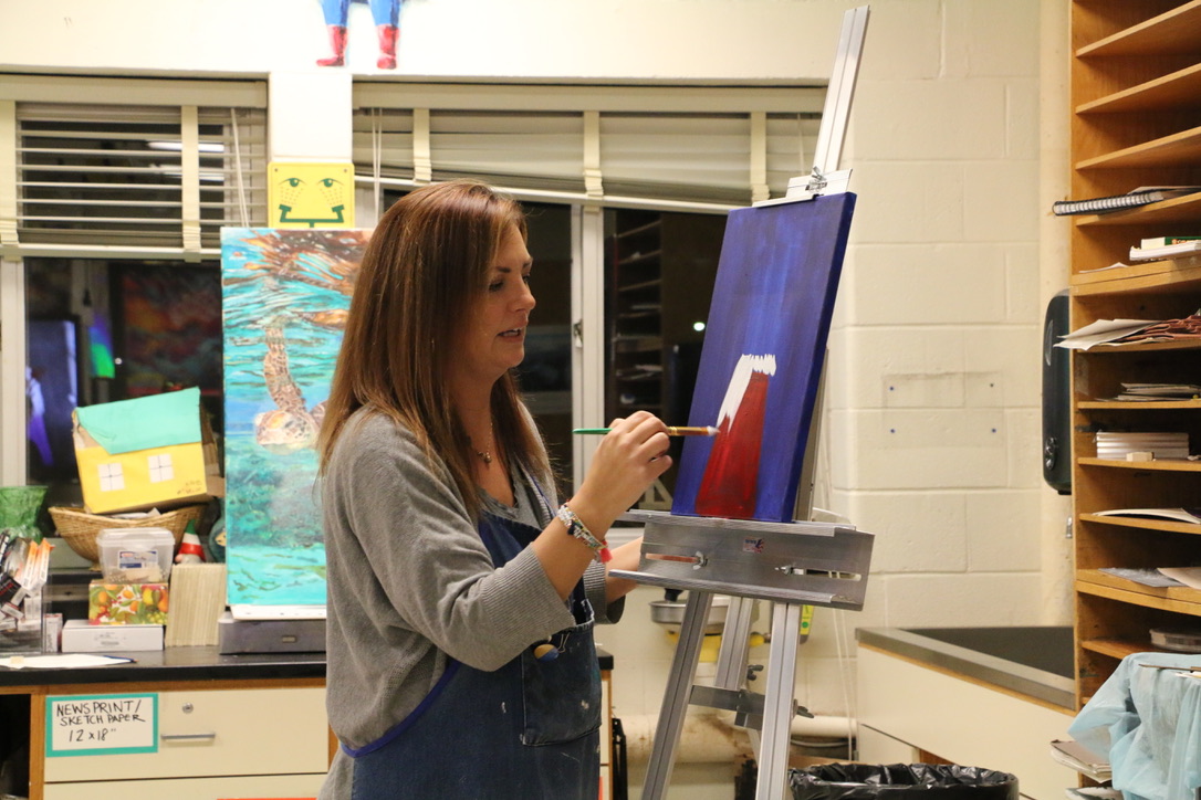 Art Teacher Mrs. Kelly Gavor demonstrating the next step for the gnome painting.