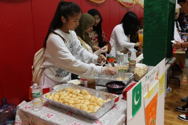 Students representing Pakistan prepare panipuri, a savory snack, to sell along with mango juice.