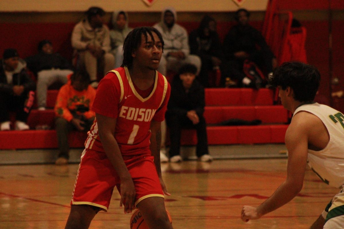 Kamir McKay '25 dribbles to move the ball across the court, looking for teammates who are open as the opponent's defense closes in.