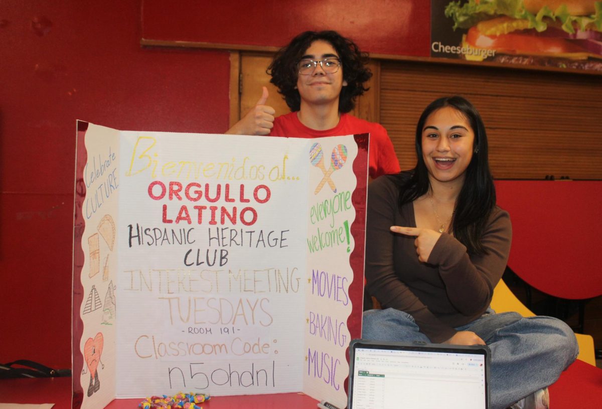 Michael Alvarez '25 (left) and April Godoy '25, the founders and board members of the new Hispanic Heritage Club, pose with their board. They promoted their new club at the Activity/Club Fair prior to the first interest meeting earlier this school year.