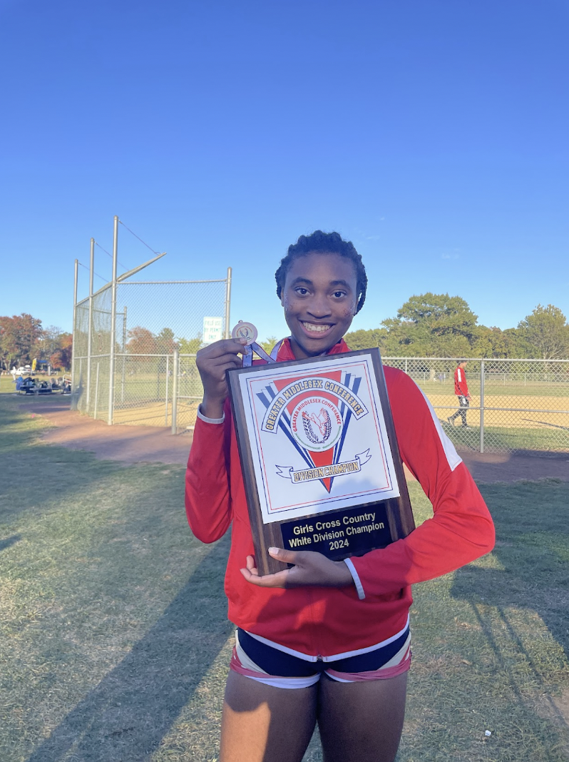 Athlete and Rotary Senior of the Month, Grace White '25, poses with her Girls Cross Country White Division Championship plaque.