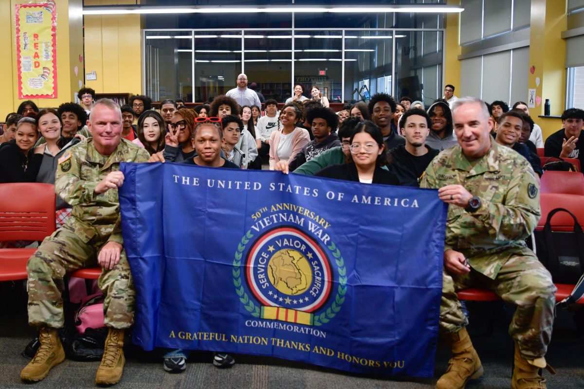 US Army Colonel Patrick Cramer (left) and Major General Edward J. Chrystal smile for a picture with Mr. Mike Glackin's US-2 classes. They are displaying a flag commemorating the 50th anniversary of the end of the Vietnam War, which was gifted to EHS by the national Vietnam War Commemoration.
