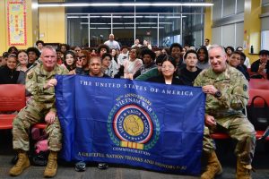 US Army Colonel Patrick Cramer (left) and Major General Edward J. Chrystal smile for a picture with Mr. Mike Glackin's US-2 classes. They are displaying a flag commemorating the 50th anniversary of the end of the Vietnam War, which was gifted to EHS by the national Vietnam War Commemoration.