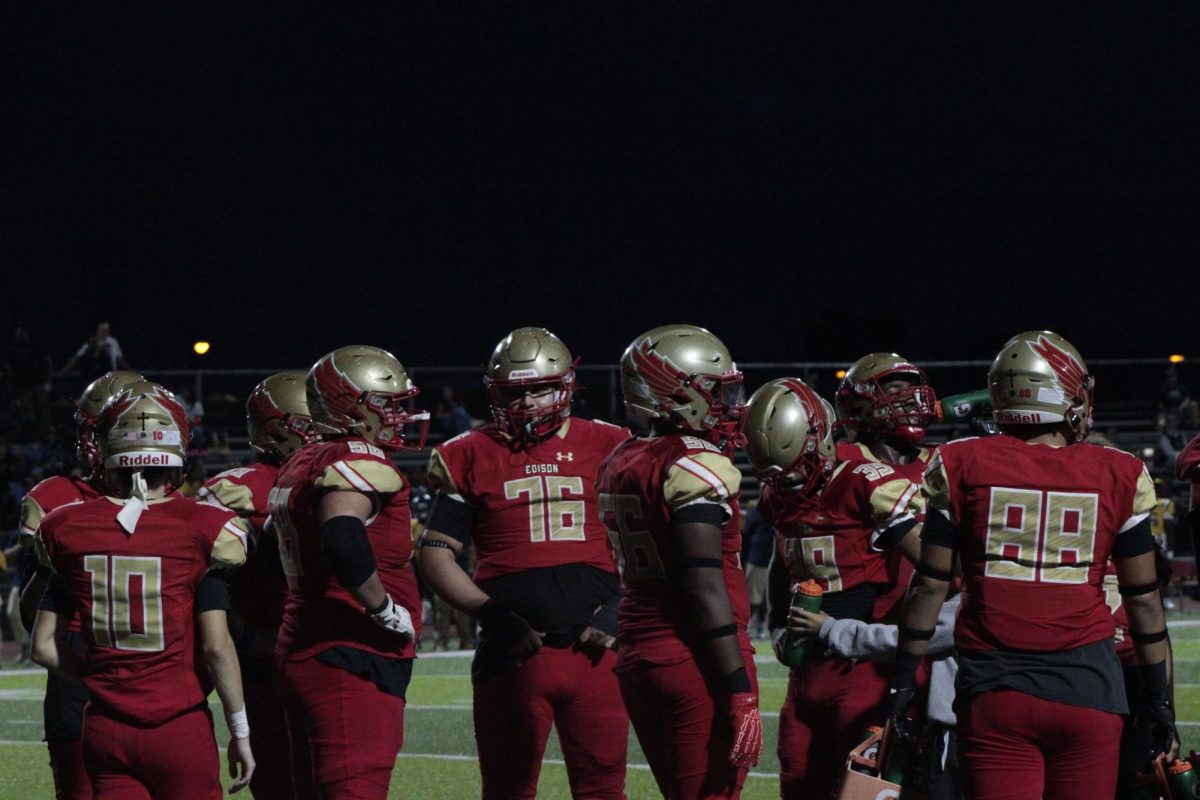 Edison football players huddle together, regrouping before the next play.