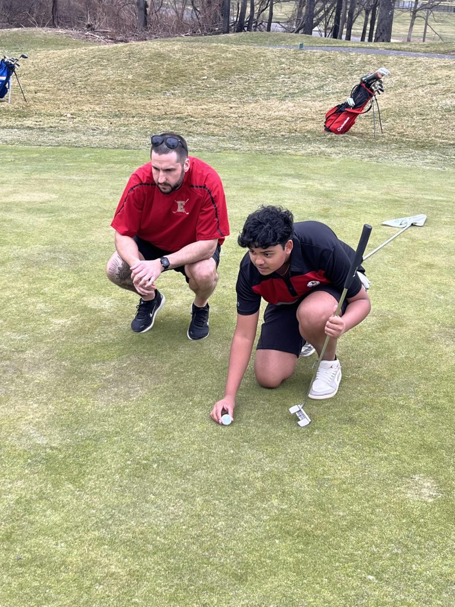 Boys Golf Coach Mr. Eric Breining assists Aarin Shrivastava '27 with lining up a putt. One of Breining's main goals as a coach is to teach his players to overcome adversity and adapt to the ever-changing environment of each course they play.