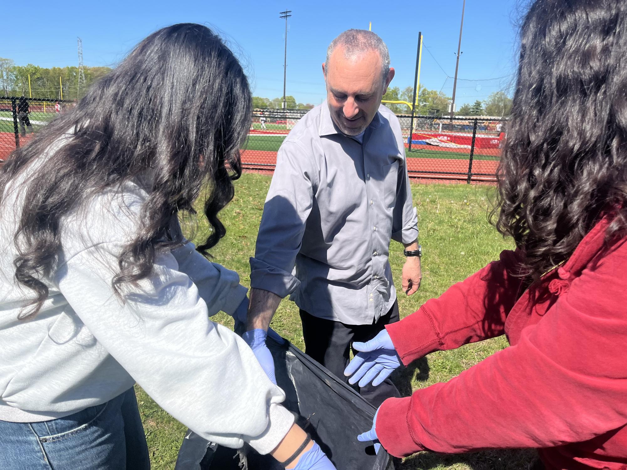 Rotary Club members Ann-maire Gonzalez ’28 and Yashaf Chaudhary ’28 work alongside advisor Mr. Howard Manson during the club's Earth Day clean-up.
