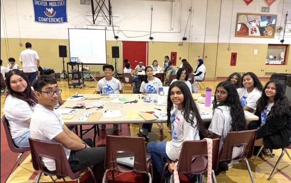Student leaders gather around a workshop table during a collaborative group activity at the RISE Student Leadership Conference.